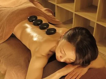 Therapist's hands arranging warmed hot stones along a client's back