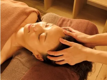 A head massage performed with both hands gently cradling the head of a reclining woman